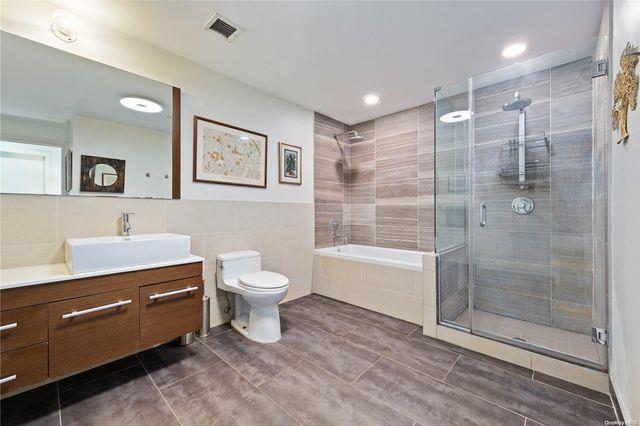 full bathroom featuring tile walls, toilet, vanity, and separate shower and tub