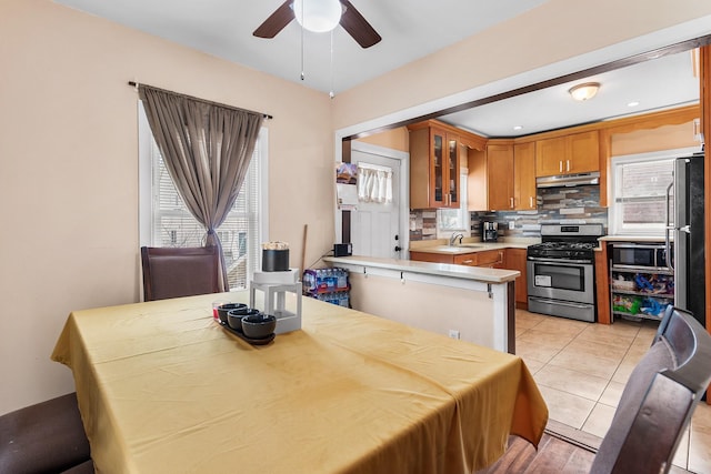 kitchen featuring sink, appliances with stainless steel finishes, tasteful backsplash, light tile patterned flooring, and kitchen peninsula