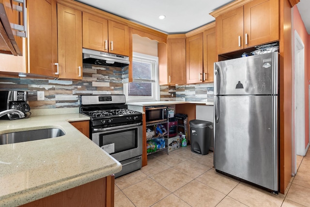 kitchen featuring appliances with stainless steel finishes, light stone countertops, sink, and backsplash