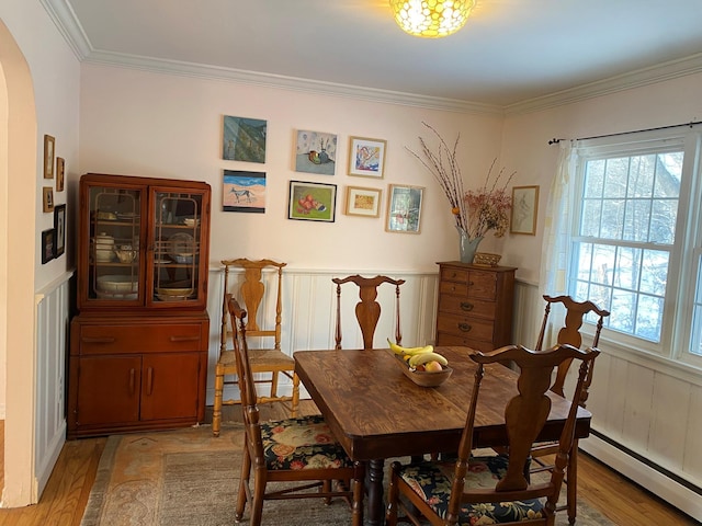 dining area featuring a baseboard heating unit, light hardwood / wood-style flooring, and crown molding