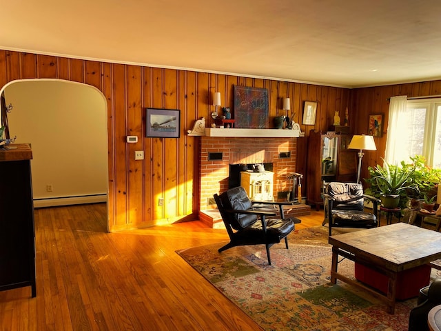 living room featuring a fireplace, a baseboard radiator, hardwood / wood-style flooring, and wooden walls