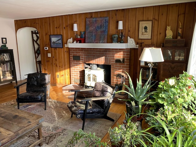 living room with a fireplace, hardwood / wood-style floors, and wooden walls