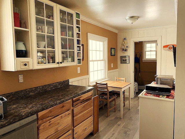 kitchen with light wood-type flooring, dishwasher, dark stone counters, and ornamental molding