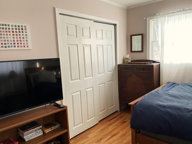 bedroom featuring a closet, crown molding, and light hardwood / wood-style floors