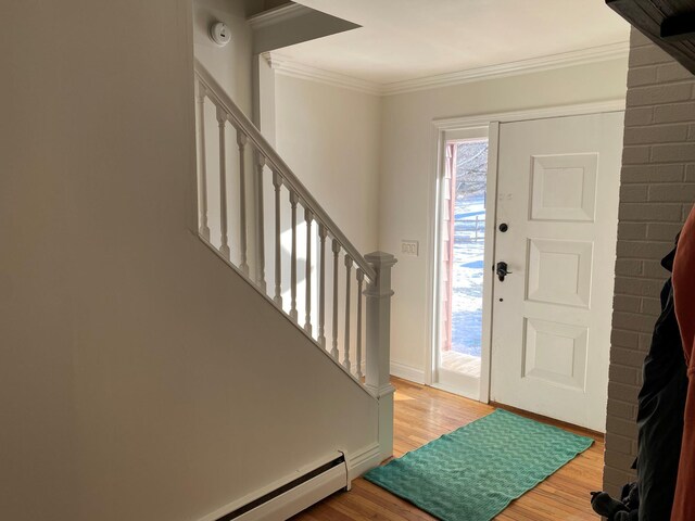 foyer with ornamental molding, light hardwood / wood-style floors, and a baseboard heating unit