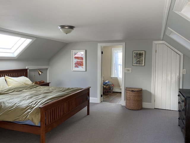 bedroom with carpet flooring, vaulted ceiling with skylight, and baseboard heating