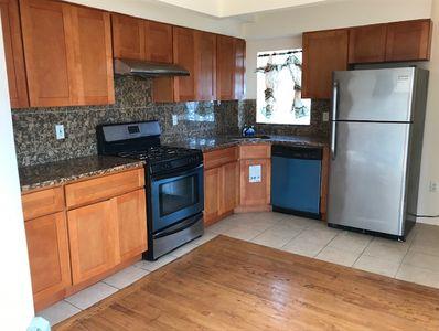 kitchen with backsplash, stainless steel appliances, light tile patterned floors, and dark stone counters