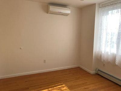 spare room featuring a baseboard heating unit, light wood finished floors, a wall mounted AC, and baseboards