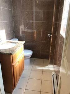 bathroom featuring toilet, tile patterned flooring, tile walls, and vanity