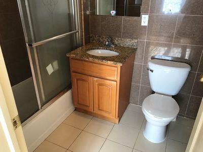 full bathroom with enclosed tub / shower combo, vanity, toilet, and tile walls