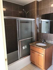 bathroom with enclosed tub / shower combo, tile walls, tile patterned floors, and vanity