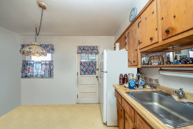 kitchen featuring sink, decorative light fixtures, white refrigerator, and backsplash