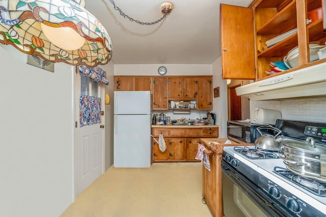 kitchen with sink, white refrigerator, black gas range, and tasteful backsplash