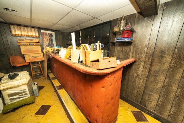 bar featuring a drop ceiling and wooden walls