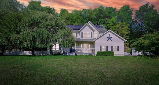 view of front of home with a porch, a lawn, and solar panels