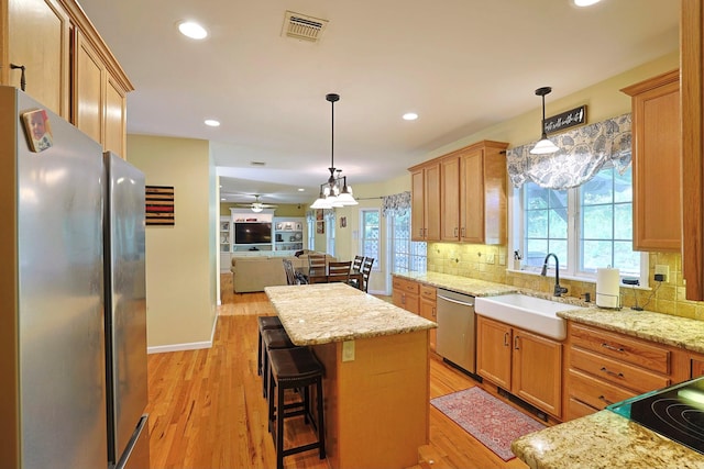 kitchen with sink, a kitchen bar, decorative backsplash, a center island, and stainless steel appliances