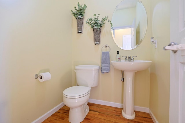 bathroom with wood-type flooring, toilet, and sink