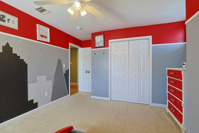 bedroom featuring light colored carpet, ceiling fan, and a closet