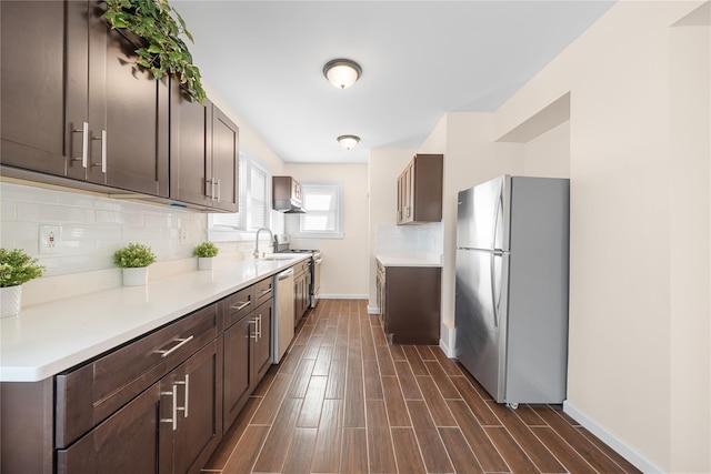 kitchen with dark brown cabinets, tasteful backsplash, and stainless steel appliances