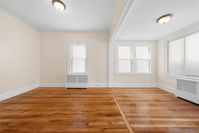 empty room featuring ornamental molding, radiator, and hardwood / wood-style floors