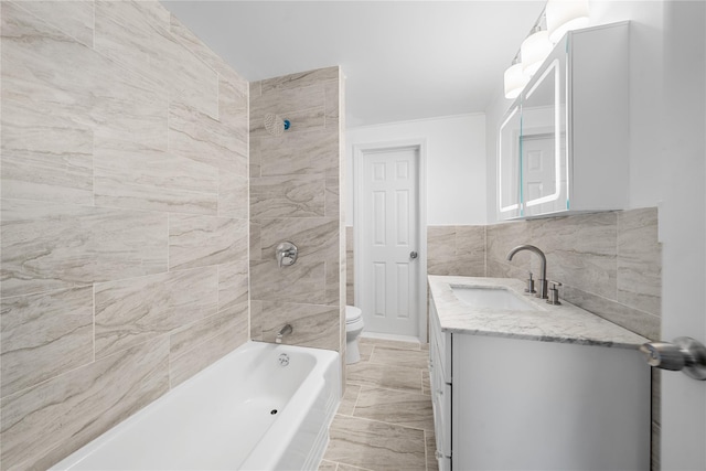 full bathroom with tiled shower / bath combo, toilet, vanity, and tile walls