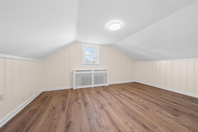 bonus room with hardwood / wood-style flooring, radiator, and lofted ceiling