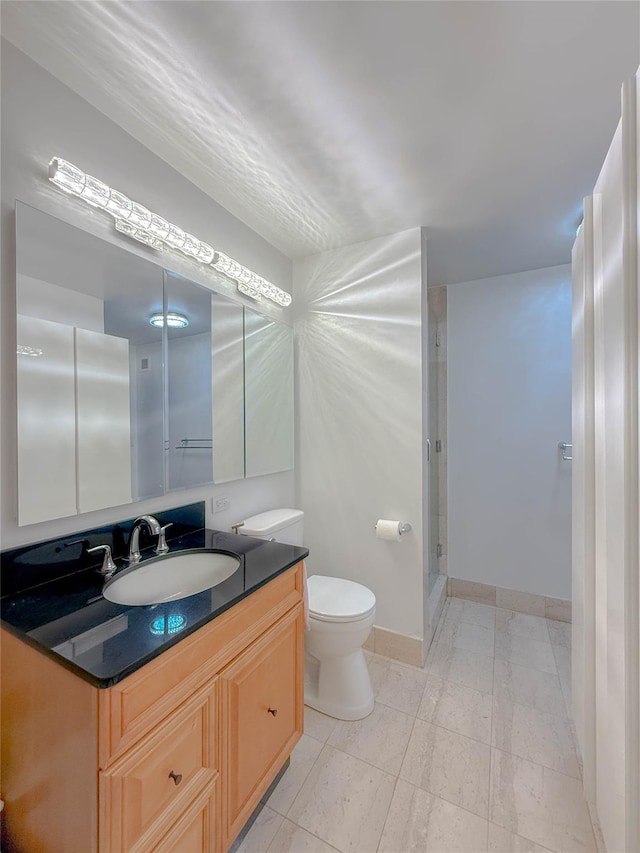 bathroom featuring vanity, toilet, and a shower with shower door