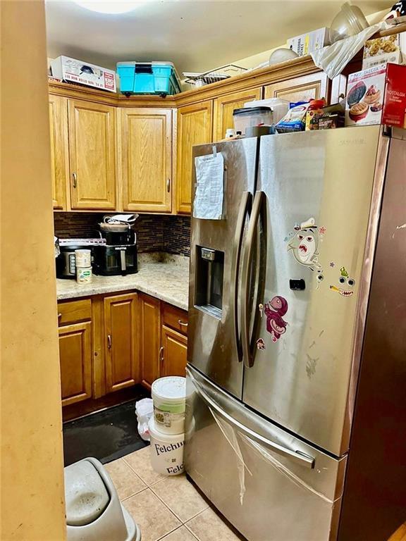 kitchen featuring stainless steel fridge with ice dispenser, backsplash, and light tile patterned floors