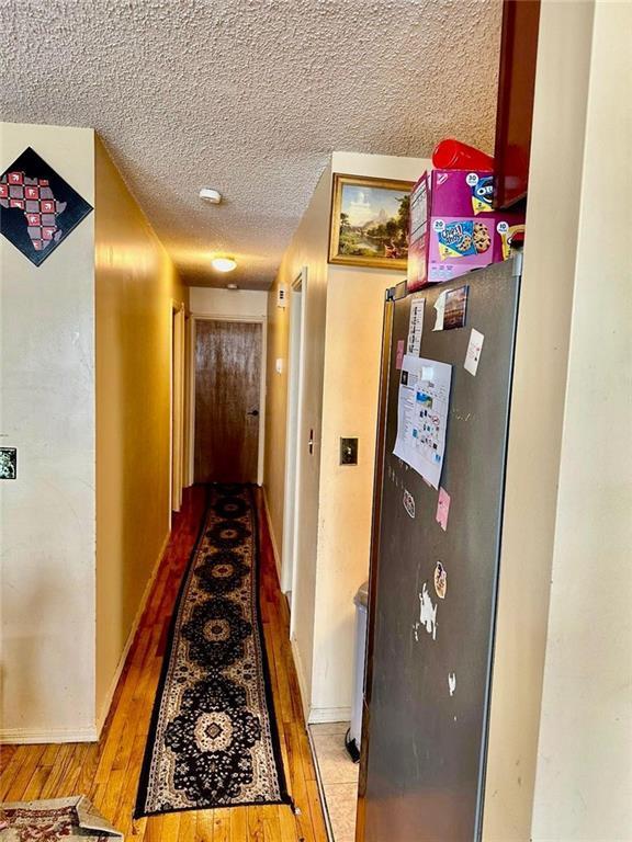 hall with hardwood / wood-style floors and a textured ceiling