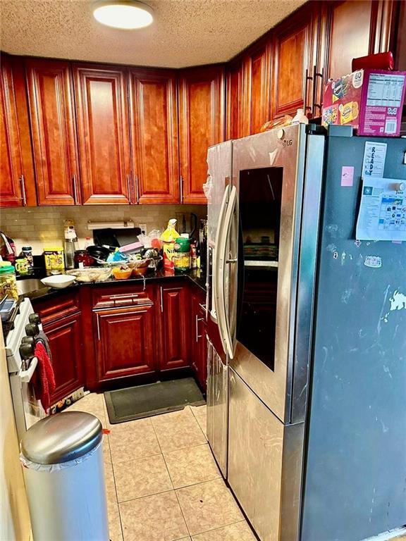 kitchen featuring light tile patterned floors, a textured ceiling, and stainless steel fridge