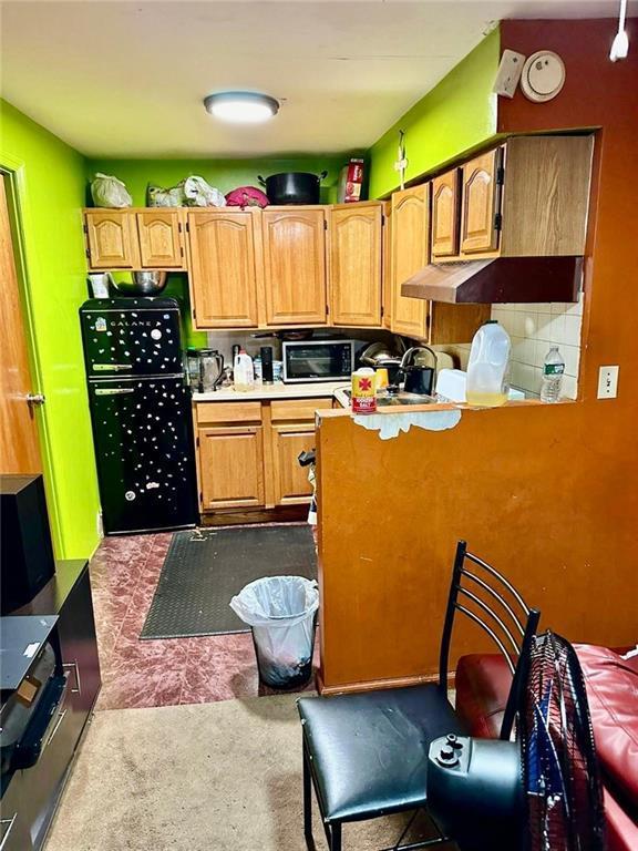 kitchen featuring backsplash, refrigerator, and carpet
