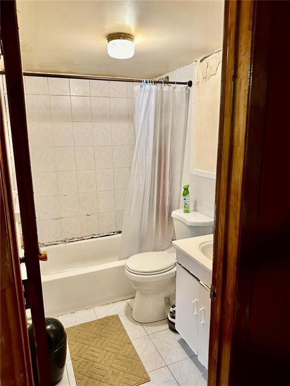 full bathroom featuring toilet, tile patterned flooring, shower / bathtub combination with curtain, and vanity