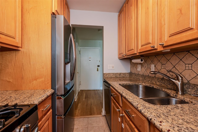 kitchen featuring light tile patterned flooring, sink, light stone counters, stainless steel fridge with ice dispenser, and black dishwasher