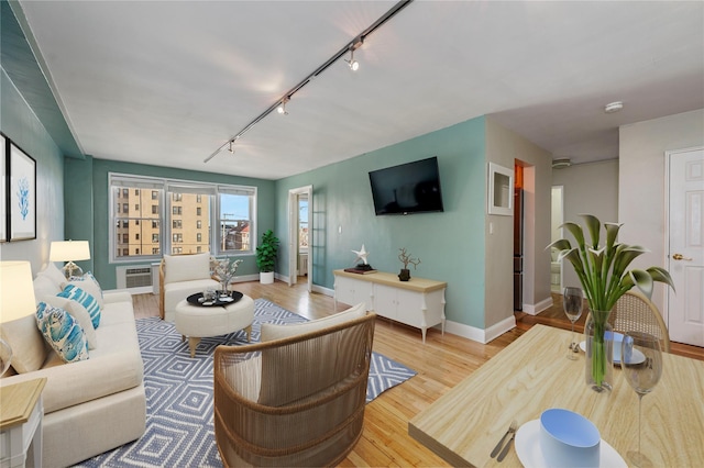 living room featuring rail lighting, an AC wall unit, and light hardwood / wood-style flooring