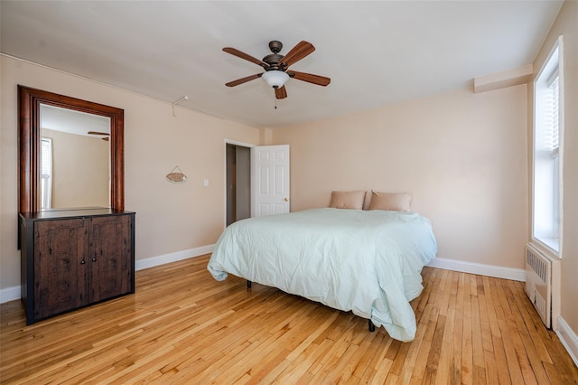 bedroom featuring ceiling fan, radiator heating unit, and light hardwood / wood-style flooring