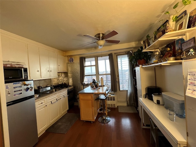 kitchen featuring a kitchen bar, tasteful backsplash, stainless steel refrigerator, dark hardwood / wood-style floors, and white cabinets