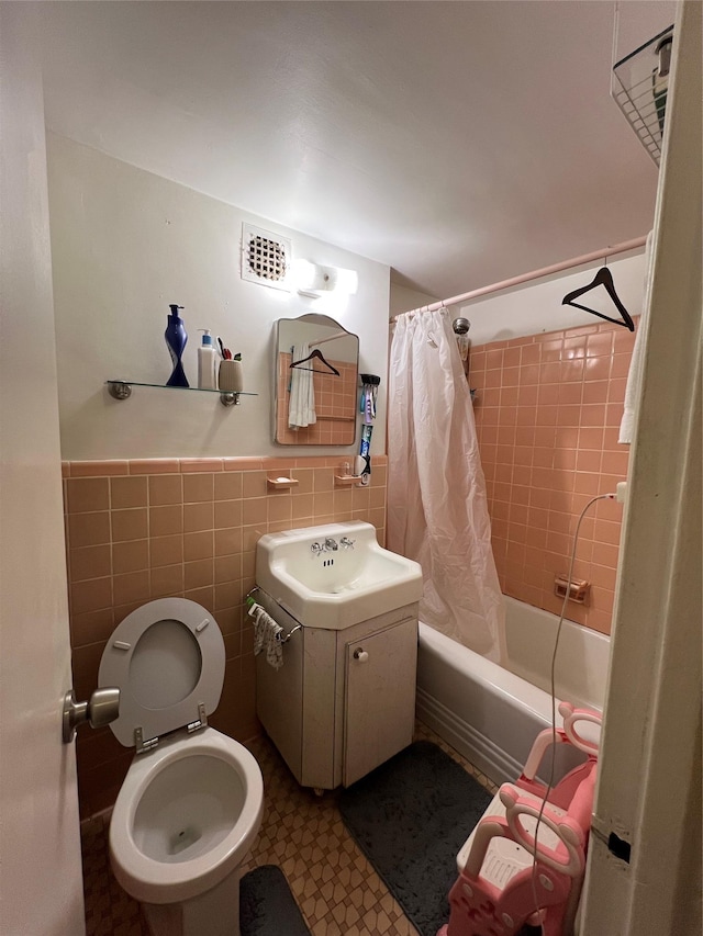 full bathroom featuring shower / bath combo, tile walls, vanity, and toilet