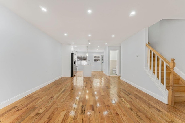 unfurnished living room featuring sink and light hardwood / wood-style flooring