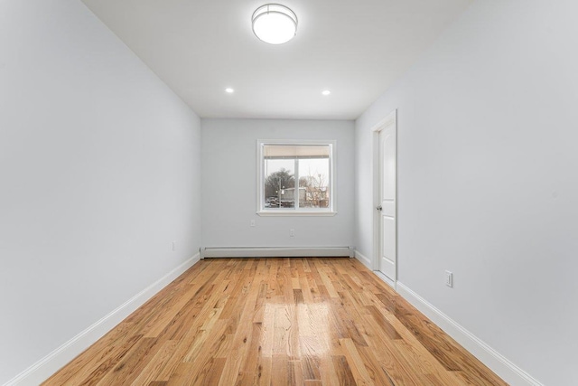 empty room with light hardwood / wood-style floors and a baseboard radiator