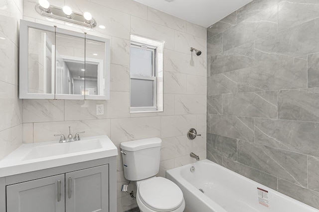 full bathroom featuring tile walls, toilet, vanity, and tiled shower / bath combo