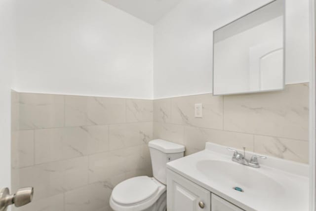 bathroom featuring tile walls, toilet, and vanity