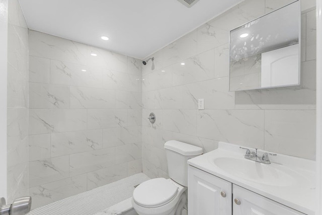 bathroom featuring a tile shower, toilet, and vanity