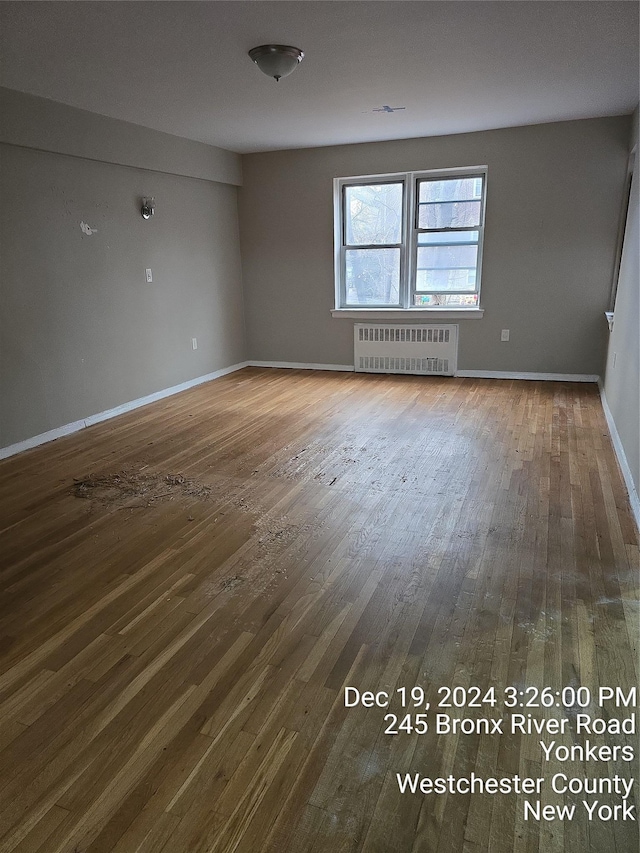 unfurnished room featuring radiator heating unit and hardwood / wood-style floors