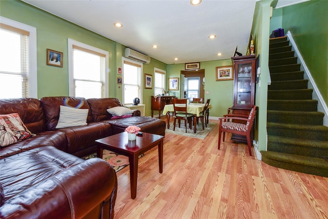 living room featuring a wall unit AC and light hardwood / wood-style floors