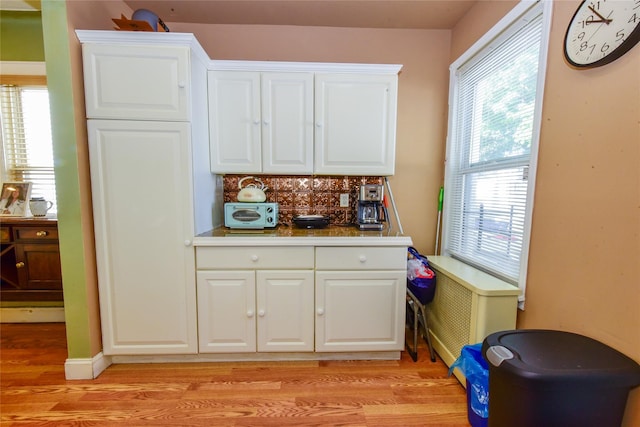 kitchen with light wood-type flooring, decorative backsplash, and white cabinets