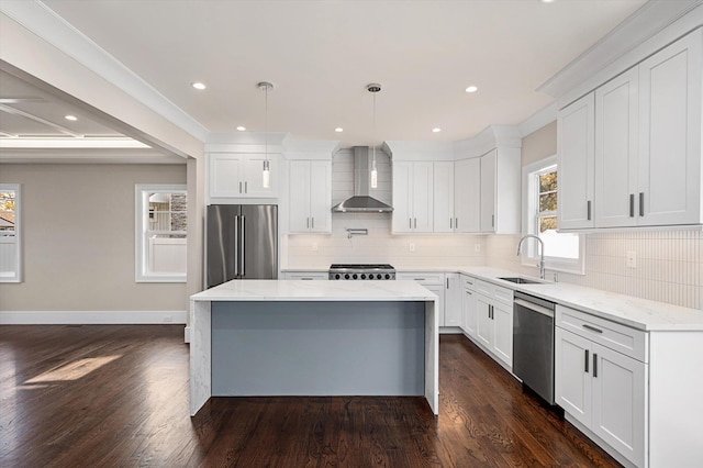 kitchen featuring sink, white cabinets, a center island, wall chimney range hood, and stainless steel appliances