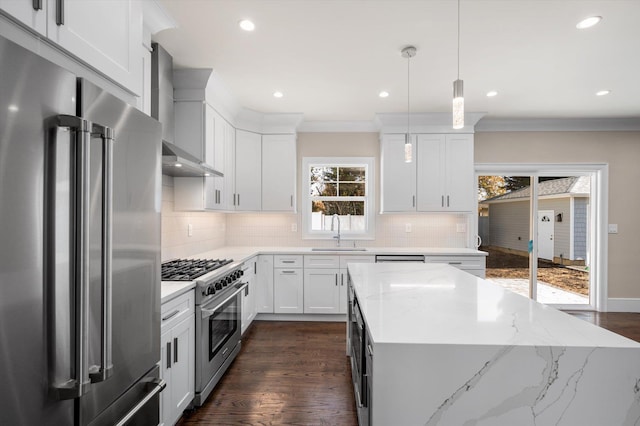 kitchen featuring white cabinets, wall chimney exhaust hood, decorative light fixtures, high end appliances, and sink