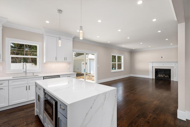 kitchen with sink, white cabinets, stainless steel microwave, and a kitchen island