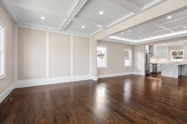 unfurnished living room with sink, coffered ceiling, and a wealth of natural light