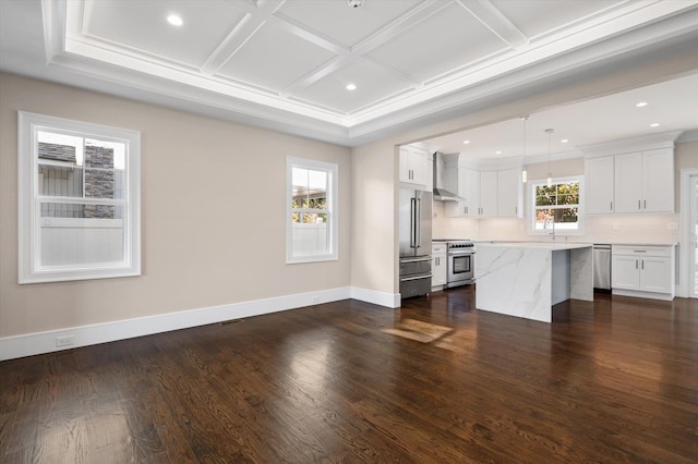 kitchen with coffered ceiling, high end appliances, white cabinetry, pendant lighting, and wall chimney exhaust hood